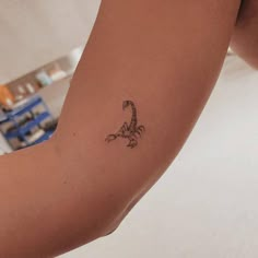 a woman's arm with a small scorpion tattoo on the left side of her arm