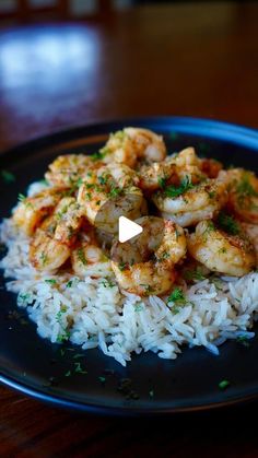 a black plate topped with rice and shrimp