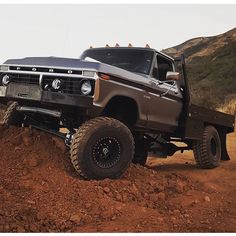 the truck is driving down the dirt road