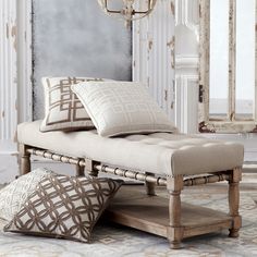 a day bed with pillows on it in front of a mirror and chandelier