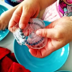 a child is holding an ice cube with berries on it in front of other plates