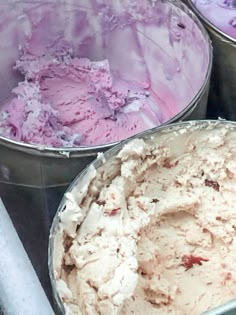 three buckets filled with ice cream sitting on top of a metal table next to each other