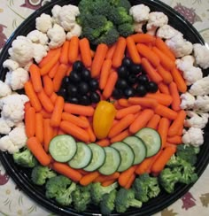 a plate with carrots, cauliflower and cucumbers arranged in the shape of a face