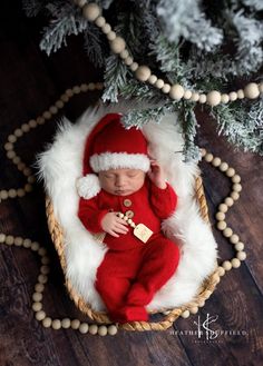 a newborn baby wearing a santa hat and sleeping in a basket