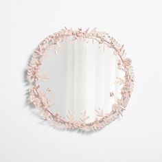 a round mirror with pink flowers on the side and a white wall in the background