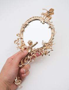 a person holding a mirror in their hand with an ornate design on the front and sides