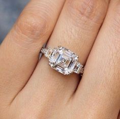 a woman's hand with an engagement ring and three stone diamond set in it