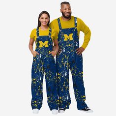 Show your team spirit in these stylish and comfortable Michigan Wolverines Women's Paint Splatter Bib Overalls. With their all-over team-colored design and bold team logo display, these overalls are the perfect way to show your support for the Michigan Wolverines while reminding everyone that your fandom is a masterpiece that even history’s greatest artists would bask in the glory of. The bib pocket is perfect for storing your phone, makeup, jewelry, skincare products, fragrances, or other essen Spirit Overalls, Spirit Jeans, Overalls Blue, Denim Ideas, Logo Display, One Piece Pajamas, Bib Overalls, Michigan Wolverines, Trendy Clothes