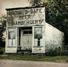 an old building with faded paint on the front and side windows that says made's cafe