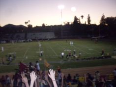 many people are watching a football game at night with their hands up in the air