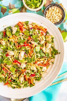 a white bowl filled with salad on top of a blue and green table cloth next to silverware