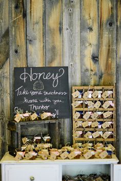 a wooden table topped with lots of small boxes filled with money next to a sign that says honey