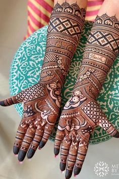 two hands with henna tattoos on them, one is showing the intricate pattern and the other