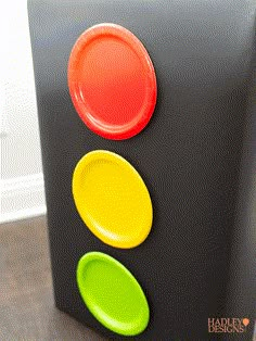 a traffic light made out of black cardboard with red, yellow and green plates on it