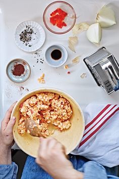 a person is holding a bowl with food on the table next to other dishes and utensils