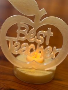 an apple shaped candle holder with the words best teacher on it