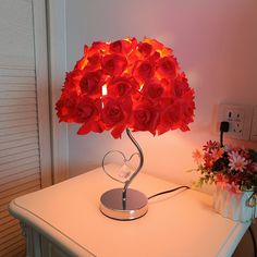 a lamp that is on top of a table with flowers in the corner next to it