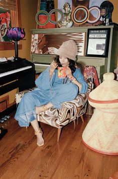 a woman is sitting on a chair in front of a piano and wearing a hat