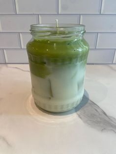 a green candle sitting on top of a counter next to a white tile backsplash