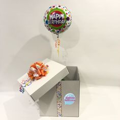 a birthday balloon in a box with confetti and streamers