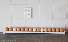 several eggs are lined up on a shelf in front of a white tile backsplash