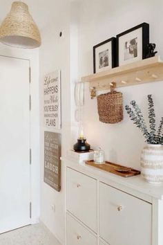 a room with white furniture and pictures hanging on the wall next to a wooden shelf