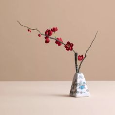 a vase with red flowers in it sitting on a table next to a brown wall