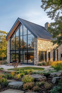 a house that is made out of stone and has a large glass window on the front