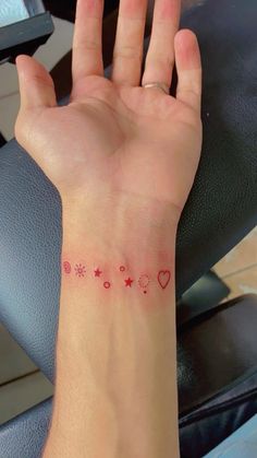 a woman's arm with a small red heart and stars tattoo on the wrist