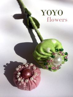 two flower brooches on a white surface with the words yoyo flowers above them