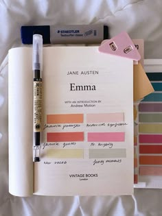 an open book with some writing on it next to a pen and color swatches