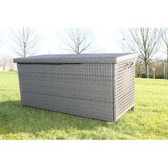 a large grey wicker storage box sitting in the middle of a grass covered field