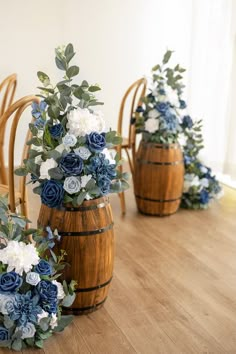 blue and white flowers sit in wooden barrels on the floor next to wicker chairs