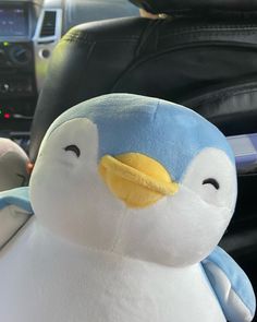 a stuffed penguin sitting in the passenger seat of a car next to a steering wheel