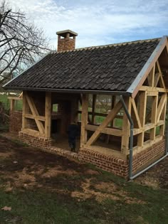 a small wooden building with a roof made out of bricks and wood shinnings