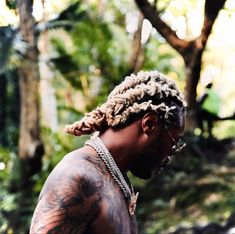 a man with dreadlocks standing in the woods