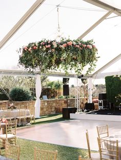 an outdoor venue with tables, chairs and flowers hanging from the ceiling over it's dance floor