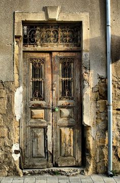 an old wooden door with wrought iron bars on the side of a stone building in europe