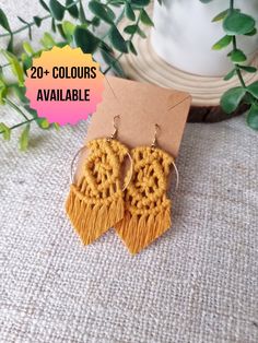 a pair of yellow earrings sitting on top of a table next to a potted plant