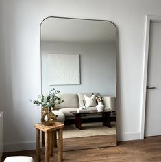 a living room filled with furniture and a large mirror on the wall next to a coffee table