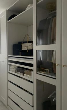 an organized closet with white cabinets and drawers