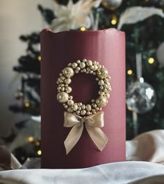 a candle with a wreath on it sitting next to a christmas tree