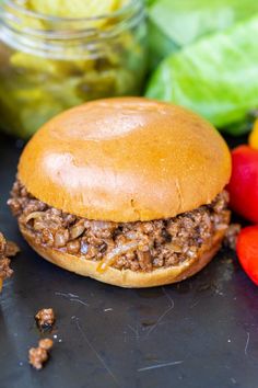 a close up of a hamburger near some vegetables