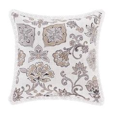 a white pillow with brown and beige floral designs on the front, along with lace trimming