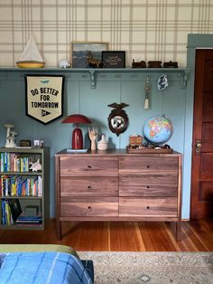 a bedroom with blue walls and wooden furniture, including a large chest of drawers in front of the bed