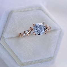 an engagement ring with a blue stone surrounded by three diamonds on top of a white cloth