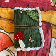 a green crocheted book with a red mushroom on it