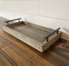 a wooden tray sitting on top of a hard wood floor next to a white wall