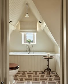 a bathroom with a toilet, sink and bathtub in the middle of an attic