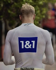 the back of a man wearing a white shirt with blue and white letters on it